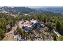 Mountain cabin nestled in the trees with a red roof and multiple decks at 3945 Douglas Mountain Dr, Golden, CO 80403