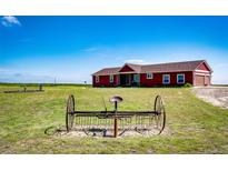 Charming red home on a sprawling green lawn under a clear blue sky at 46122 County Road 53, Bennett, CO 80102