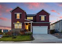 Beautiful two-story home with a two car garage and a combination stone and siding exterior under a colorful sky at 4825 Basalt Ridge Cir, Castle Rock, CO 80108