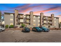 Exterior view of a multi-story apartment building featuring stone accents and balconies at sunset at 381 S Ames St # E305, Lakewood, CO 80226