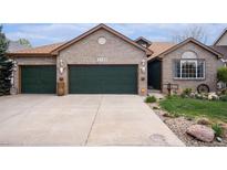 Charming brick home featuring a three-car garage, manicured lawn, and decorative exterior details at 2190 Coyote Creek Dr, Fort Lupton, CO 80621