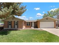 Charming brick home with mature trees, a well-maintained lawn, and an attached two-car garage at 2964 S Akron St, Denver, CO 80231