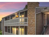 Condo exterior with stone accents, white railing, and well-lit windows at dusk at 18133 E Kentucky Ave # 203, Aurora, CO 80017