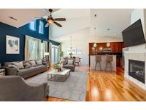 Bright living room boasts vaulted ceilings, hardwood floors, fireplace, and open floor plan to kitchen and dining area at 6742 S Winnipeg Cir # 105, Aurora, CO 80016