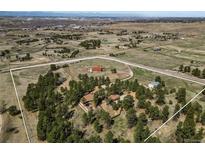Expansive aerial view of a beautiful property with mature trees, horse facilities, and a charming home in a serene setting at 7076 Inspiration Dr, Parker, CO 80138