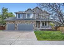 Charming two-story home featuring a stone facade, attached garage, and a covered porch, complemented by a well-maintained lawn at 13330 York Way, Thornton, CO 80241