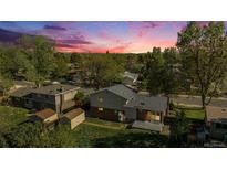Aerial view of home nestled among mature trees and surrounded by lush green lawns at sunset at 9345 W Iowa Pl, Lakewood, CO 80232
