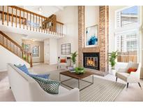 Inviting living room boasts a brick fireplace, staircase and a soaring vaulted ceiling at 1566 S Syracuse St, Denver, CO 80231