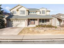 Charming two-story home boasts beautiful brick accents, a covered porch, and a well-manicured front yard at 17101 W 64Th Dr, Arvada, CO 80007