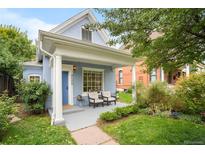 Charming light blue home featuring a covered porch with white columns and a well-manicured front yard at 4508 W 34Th Ave, Denver, CO 80212