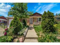 Charming single-story home featuring a well-maintained lawn, beautiful flower beds, and a welcoming front porch at 7101 Alan Dr, Denver, CO 80221