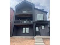 Modern three-story home with dark siding, double balconies, and covered porch at 8858 Waterleaf Ln, Littleton, CO 80125