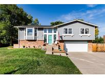 Charming home featuring a manicured lawn, brick accents, and a striking turquoise front door at 8063 S Otis Ct, Littleton, CO 80128