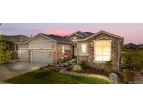 Charming home featuring a manicured lawn, stone accents, and a convenient three-car garage at 8691 S Sicily Ct, Aurora, CO 80016