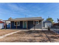 Gray house with green door, covered porch, and detached garage at 7780 Hollywood St, Commerce City, CO 80022