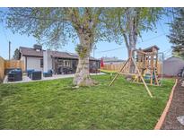 Spacious backyard featuring a patio, lush lawn, mature trees, a hammock and playset at 1655 S Lowell Blvd, Denver, CO 80219
