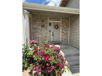 Charming front entry featuring a wreath, brick facade, and vibrant rose bushes, creating an inviting welcome at 12089 W Burgundy Ave, Littleton, CO 80127