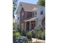 Charming townhome with brick and siding, a red front door, and landscaped yard at 8802 E 24Th Pl # 101, Denver, CO 80238