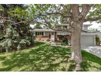 Charming two-story home with brick accents, lush lawn, mature trees and manicured landscaping at 6211 S Garfield Dr, Centennial, CO 80121