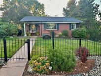 Charming brick home with black fence and manicured front yard landscaping at 2527 S Vine St, Denver, CO 80210