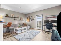 Bright living room with a cozy gray sofa and balcony access, perfect for relaxing or entertaining at 975 N Lincoln St # 12J, Denver, CO 80203