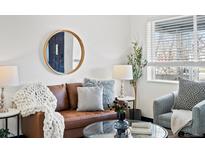 Cozy living room features a brown leather couch, round mirror, and ample natural light at 4842 Steele St, Denver, CO 80216