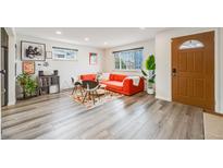 Bright living room features sleek gray wood flooring and a stylish red sofa at 1308 W 102Nd Ave, Northglenn, CO 80260