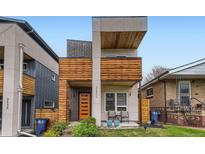 Modern home with a unique wood facade, orange front door, and well-maintained landscaping at 3632 N Pecos St, Denver, CO 80211