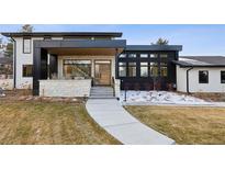 Striking modern two-story home with a stone facade, black accents, and a walkway leading to a contemporary wood front door at 17326 W 57Th Ave, Golden, CO 80403