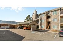Apartment building with covered parking, stone accents, and mountain views at 7459 S Alkire St # 202, Littleton, CO 80127
