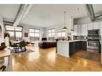 Bright, open-concept living and kitchen area with hardwood floors and stainless steel appliances at 2900 N Downing St # 311, Denver, CO 80205