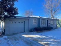 Charming single-story home featuring a front yard, an attached garage and a well-maintained yard with snow at 1180 Walnut St, Brighton, CO 80601