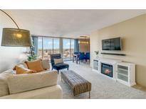 Bright living room features a fireplace, large windows, and city views at 955 Eudora St # 708E, Denver, CO 80220