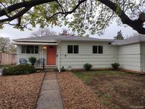 Charming single-story home with a tidy front yard, sidewalk, and a vibrant coral-colored front door at 5115 Bryant St, Denver, CO 80221