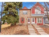 Charming townhouse featuring a stone facade, red shutters, and well-maintained landscaping at 11901 E Kepner Dr, Aurora, CO 80012