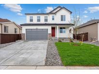 Beautiful two-story home featuring an attached two-car garage, well-manicured lawn, and charming red door at 19120 E 96Th Pl, Commerce City, CO 80022