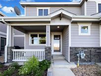 Charming home featuring a welcoming front porch with stone accents and beautiful landscaping at 6108 Kochia Ct # 104, Erie, CO 80516