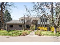 Charming two-story brick home with a manicured lawn, mature trees, and inviting curb appeal on a sunny day at 1448 E Maplewood Ct, Centennial, CO 80121