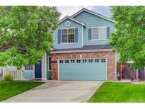 Charming two-story home featuring a brick facade, blue siding, a well-manicured lawn and mature shade trees at 15828 Greenstone Ln, Parker, CO 80134