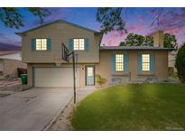 Charming home with a two-car garage, a basketball hoop, and blue shutters under a sky filled with sunset colors at 1549 S Evanston St, Aurora, CO 80012