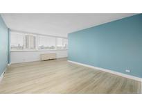 Bright living room with light wood floors, blue accent wall, and large windows with city views at 1196 N Grant St # 705, Denver, CO 80203