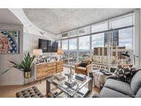 Bright living room features floor-to-ceiling windows with city views, hardwood floors, and modern furnishings at 891 14Th St # 2703, Denver, CO 80202