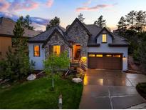 Charming stone and stucco home featuring a well-manicured lawn and inviting curb appeal at dusk at 6840 Northstar Cir, Castle Rock, CO 80108