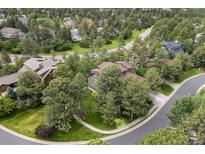 Aerial view of a wooded neighborhood with a brown two story house featuring mature trees and lush landscaping at 1122 Forest Trails Dr, Castle Pines, CO 80108
