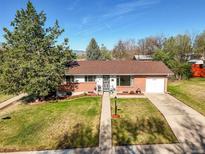 Charming single-story home with a manicured lawn, blue sky, and mountain views in the distance at 3061 S Mabry Ct, Denver, CO 80236