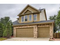 Two car garage with stone accents, neutral doors and dark roof at 5553 Jasper St, Denver, CO 80239