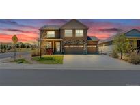 Inviting two-story home featuring a stone facade, three-car garage, and a well-manicured front lawn at sunset at 2177 Shadow Creek Dr, Castle Rock, CO 80104