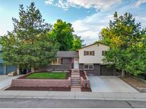 Charming split-level home featuring a brick facade, lush landscaping, and inviting curb appeal at 9123 W Arbor Ave, Littleton, CO 80123