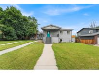Charming home featuring gray brick, lush green lawn, walkway and vibrant blue front door with covered porch at 1655 Yates St, Denver, CO 80204
