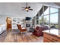 Bright living room featuring a stone fireplace, built-in shelves, and large windows with scenic views at 1391 S Winston Dr, Golden, CO 80401